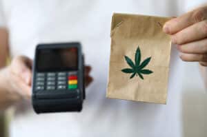 Man with POS device and a small bag of cannabis
